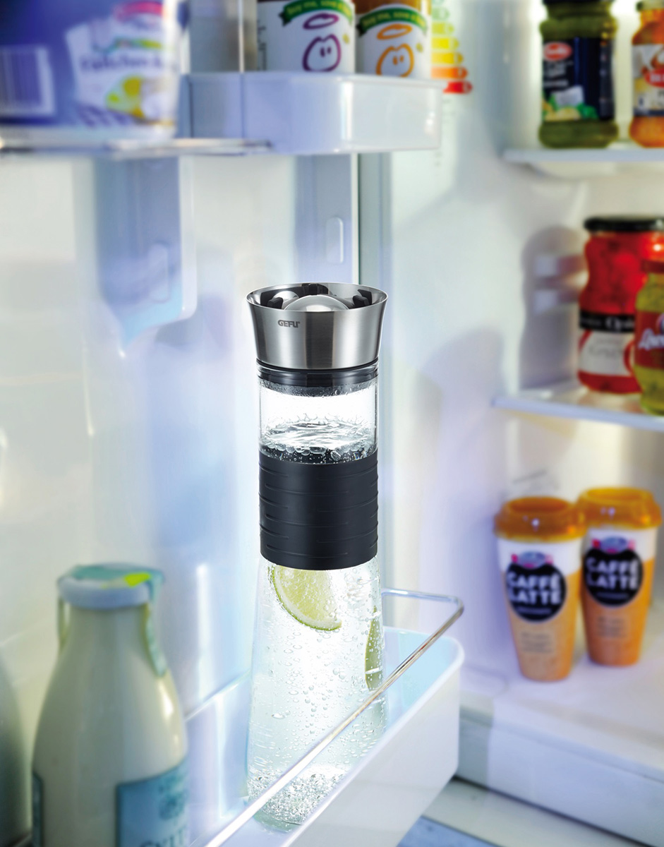 Wasserkaraffe mit Zitrone und Edelstahlverschluss im Kühlschrank Klare Wasserkaraffe mit schwarzem Griff und Edelstahlverschluss, gefüllt mit Zitronenscheiben, in einem Kühlschrank