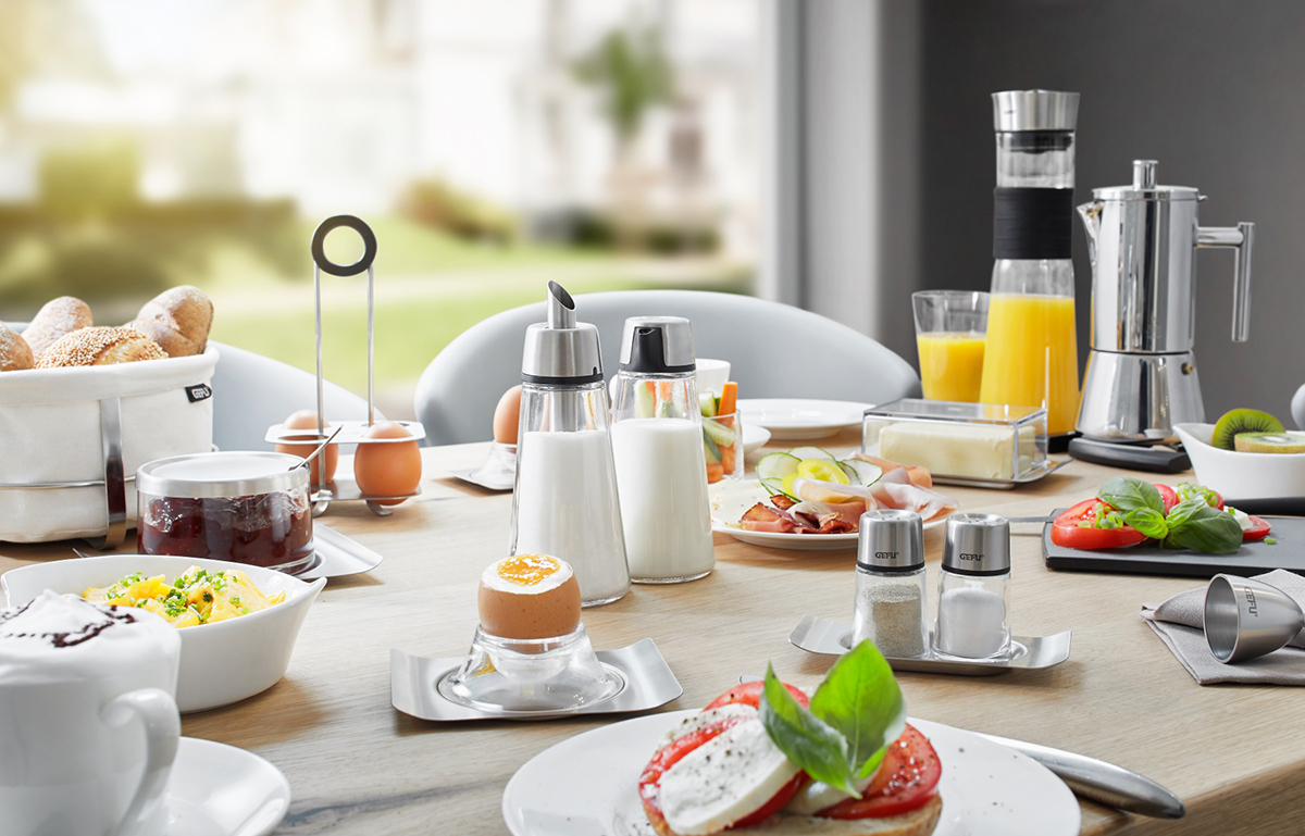 Elegantes Frühstücksset für den modernen Esstisch Frühstückstisch mit Brötchen, Eiern, Saftkaraffe und Geschirr