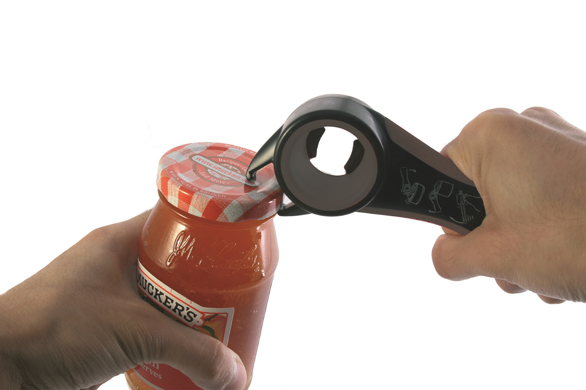Glasöffner in Aktion: Einfaches Öffnen eines Marmeladenglases Ein Glasöffner wird verwendet, um den Deckel eines Marmeladenglases zu öffnen. Zwei Hände halten den Glasöffner und das Glas um einen festen Griff zu gewährleisten.